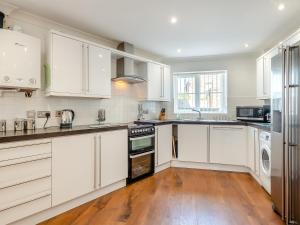 a kitchen with white cabinets and a wooden floor at Sandbanks in Bacton +15 photos