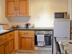 a kitchen with a stove and a white refrigerator at Walnut Tree Cottage in Burbage