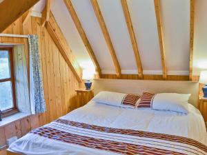 a bed in a room with wooden walls and a window at Walnut Tree Cottage in Burbage