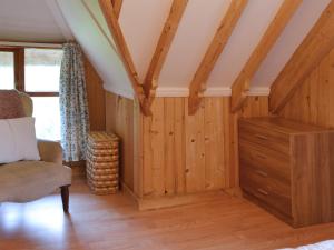 a room with wooden walls and a chair and a dresser at Walnut Tree Cottage in Burbage