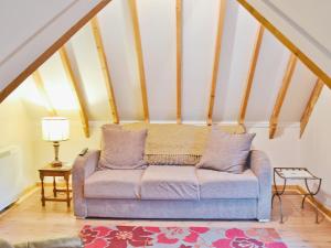 a living room with a couch in the attic at Walnut Tree Cottage in Burbage