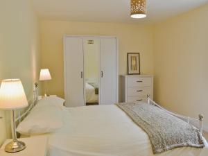 a bedroom with a white bed and a mirror at Hornbeam Cottage in Malvern Wells