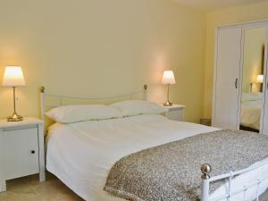 a bedroom with a large white bed with two lamps at Hornbeam Cottage in Malvern Wells
