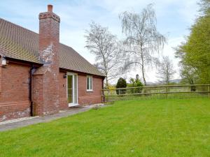a brick house with a fence and a yard at Hornbeam Cottage in Malvern Wells +4 photos