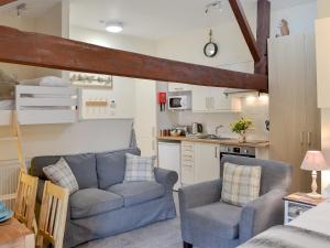 a living room with a couch and chairs in a kitchen at Barn Owl Bothy in Westward