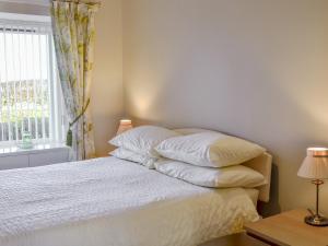 a bedroom with a bed with pillows and a window at Eliza Cottage in Haddington