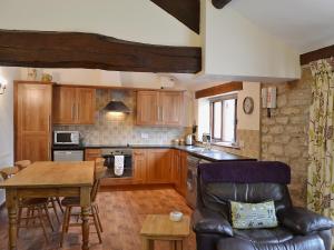 a kitchen with wooden cabinets and a table and a chair at Elm Tree Cottage in Kirkbymoorside