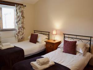 a bedroom with two beds and a window at Elm Tree Cottage in Kirkbymoorside