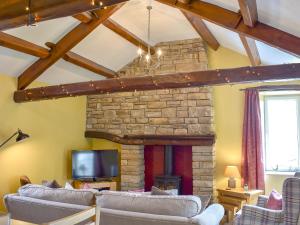 a living room with couches and a stone fireplace at Timbessie Barn in Carperby