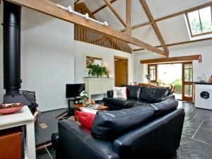 a living room with a black leather couch at The Smithy in Chulmleigh
