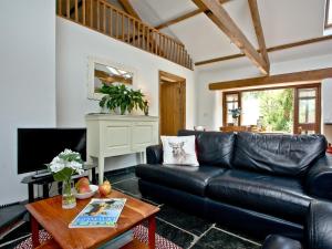 a living room with a black leather couch and a table at The Smithy in Chulmleigh