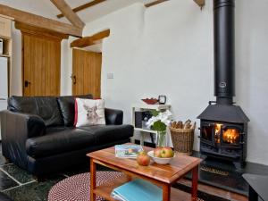 a living room with a black leather couch and a wood stove at The Smithy in Chulmleigh