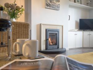 a living room with a fire in a fireplace at Cuthbert Cottage in Craster