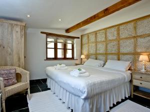 a bedroom with a large white bed and a chair at The Smithy in Chulmleigh +17 photos
