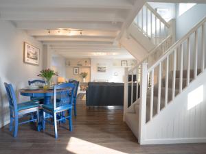a dining room with a table and blue chairs at Cuthbert Cottage in Craster
