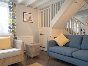 a living room with a blue couch and chairs at Cuthbert Cottage in Craster