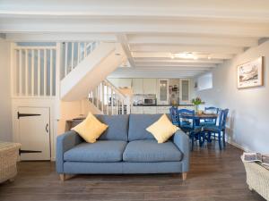 a living room with a blue couch and a kitchen at Cuthbert Cottage in Craster