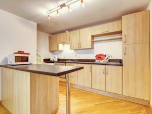 a kitchen with wooden cabinets and a black counter top at 5 Red Rock Apartments in Dawlish Warren +10 photos