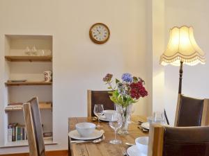a dining room table with a vase of flowers and a clock at Old Post Office House in Knockbain