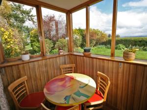 a porch with a table and chairs and a window at Old Post Office House in Knockbain