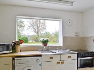 a kitchen with a sink and a window at Old Post Office House in Knockbain