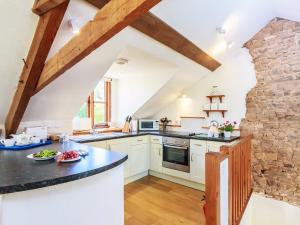 a kitchen with white cabinets and a stone wall at Cider Barn in Chulmleigh