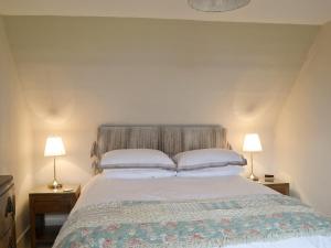 a bedroom with a large bed with two lamps at Old Post Office House in Knockbain
