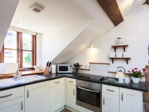 a kitchen with white cabinets and black counter tops at Cider Barn in Chulmleigh +16 photos
