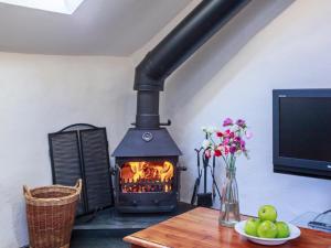 a fireplace in a room with a table and a television at Cider Barn in Chulmleigh
