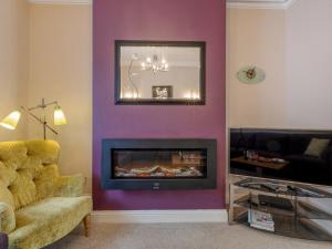 a living room with a purple wall with a fireplace at Jame's Cottage in Keswick
