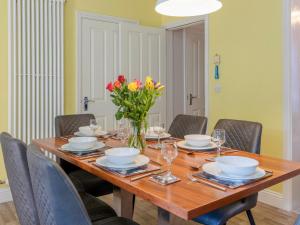 a dining room table with chairs and a vase of flowers at Jame's Cottage in Keswick