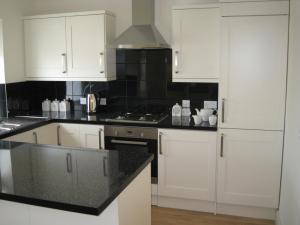 a kitchen with white cabinets and black counter tops at Swallow's Nest in Bradwell
