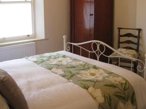 a bed with a blanket with flowers on it at Swallow's Nest in Bradwell +6 photos