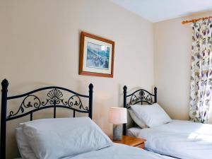 a bedroom with two beds and a picture on the wall at Gran's Cottage Askrigg in Askrigg