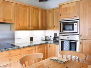 a kitchen with wooden cabinets and a wooden table with chairs at Gran's Cottage Askrigg in Askrigg