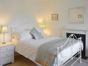 a bedroom with a white bed and a fireplace at Viewington Lodge in Ballater