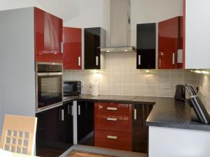 a kitchen with red cabinets and black counter tops at Viewington Lodge in Ballater