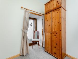 a room with a wooden cabinet and a chair at The Byre Mey in Scarfskerry