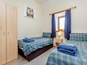 a bedroom with two beds and a window with blue curtains at The Byre Mey in Scarfskerry +8 photos