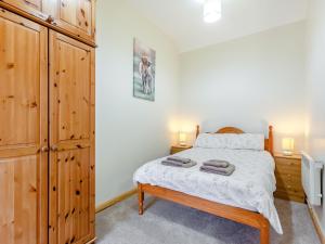 a bedroom with a bed and a wooden cabinet at The Byre Mey in Scarfskerry