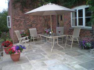 a patio with a table and chairs and an umbrella at Farmhouse Cottage in North Rode