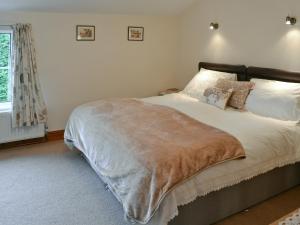 a bedroom with a bed with a blanket on it at Farmhouse Cottage in North Rode