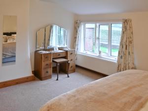 a bedroom with a bed and a dresser with a mirror at Farmhouse Cottage in North Rode