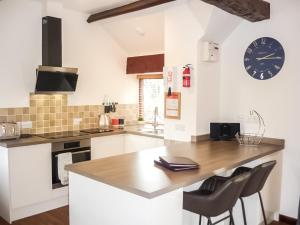 a kitchen with a counter and a clock on the wall at Plum Tree Cottage in Kirkbymoorside
