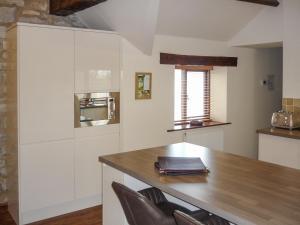 a kitchen with white cabinets and a wooden table at Plum Tree Cottage in Kirkbymoorside