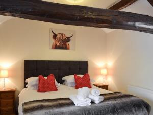 a bedroom with a bed with towels and a bull on the wall at Plum Tree Cottage in Kirkbymoorside