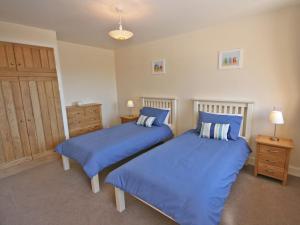two beds in a bedroom with blue sheets at Cairndoon Steading Whithorn in Carlton