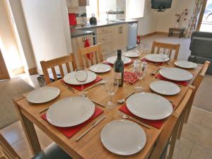 a wooden table with plates and wine glasses on it at Cairndoon Steading Whithorn in Carlton
