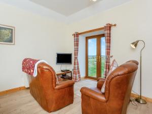 a living room with two leather chairs and a television at The Barn Mey in Scarfskerry