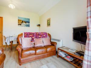 a living room with a leather couch and a television at The Barn Mey in Scarfskerry